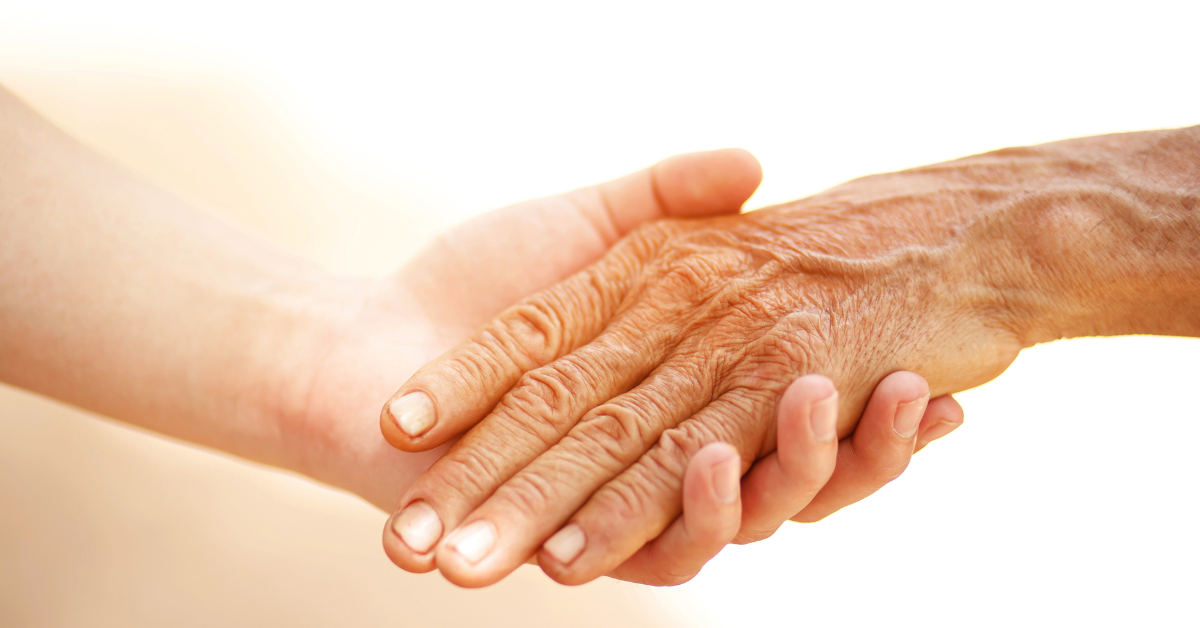 An elderly person holding hands with a caregiver